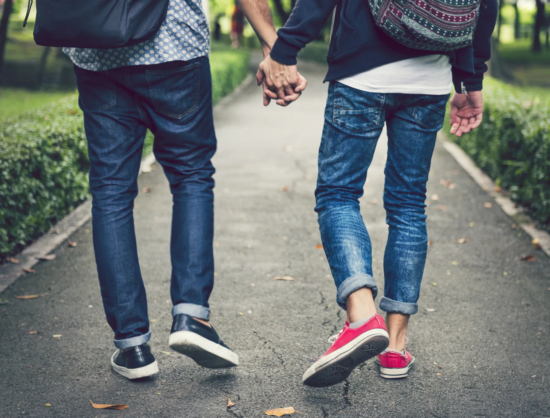 Two partners walking hand in hand down a tree-lined path
